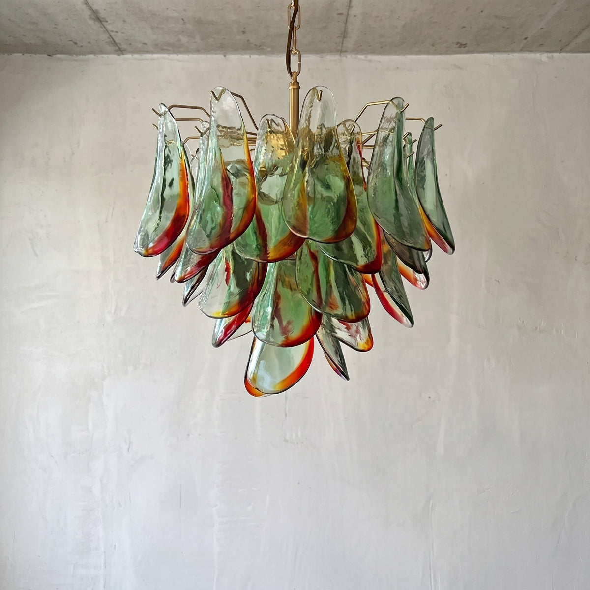 Détail du cadre en acier inoxydable finition laiton, supportant les éléments de verre coloré de ce lustre au design vintage.