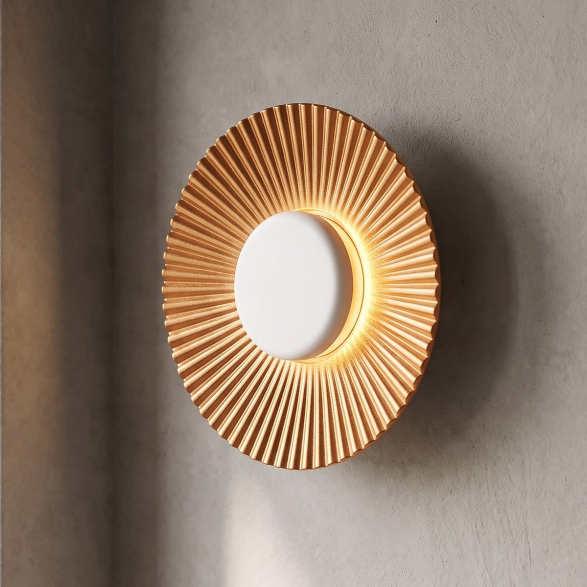 Applique murale LED moderne en aluminium finition dorée et blanche, diamètre 16cm, allumée pour une lumière chaleureuse dans un intérieur.