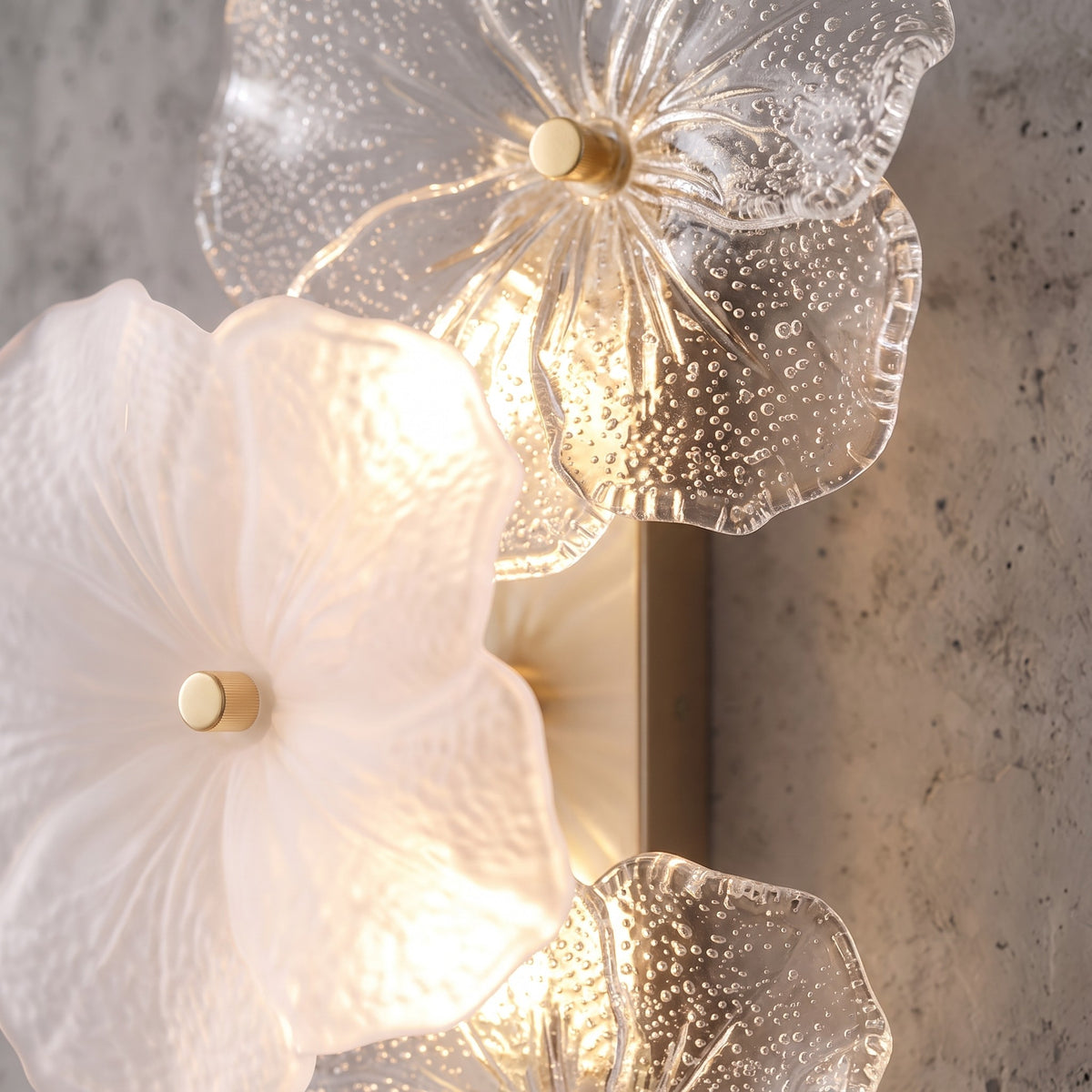 Détail d'une fleur d'applique murale en verre soufflé artisanal, montrant la texture délicate des pétales givrés.