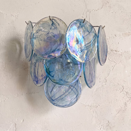 Applique murale style Murano vintage bleue, composée de disques de verre irisés, éclairant un salon moderne avec élégance.