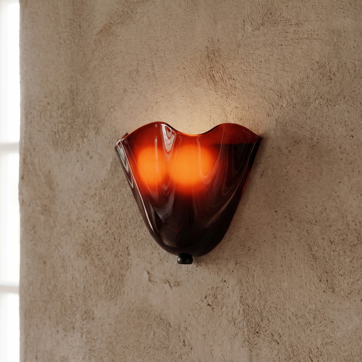 Applique murale vintage style Murano en verre soufflé ambré, diffusant une lumière chaude et accueillante sur un mur clair.