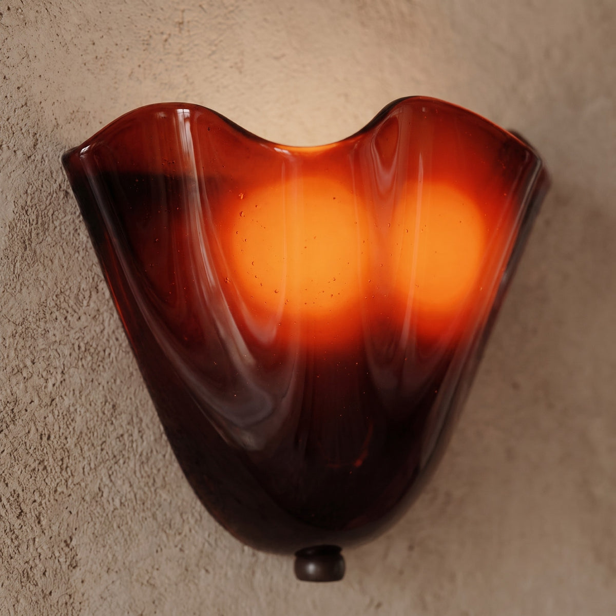 Détail de l'applique murale ambrée, montrant la texture et les reflets du verre plissé de style artisanal.