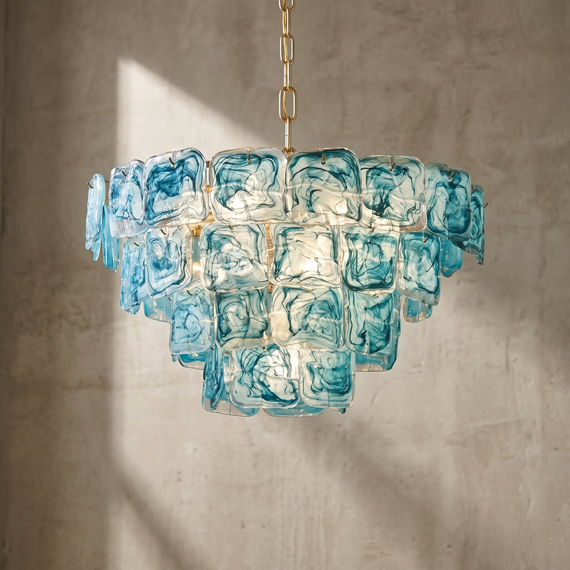 Vue d'ensemble d'un grand lustre style Murano, verre bleu-vert aquatique et structure dorée, éclairant un salon moderne avec élégance.