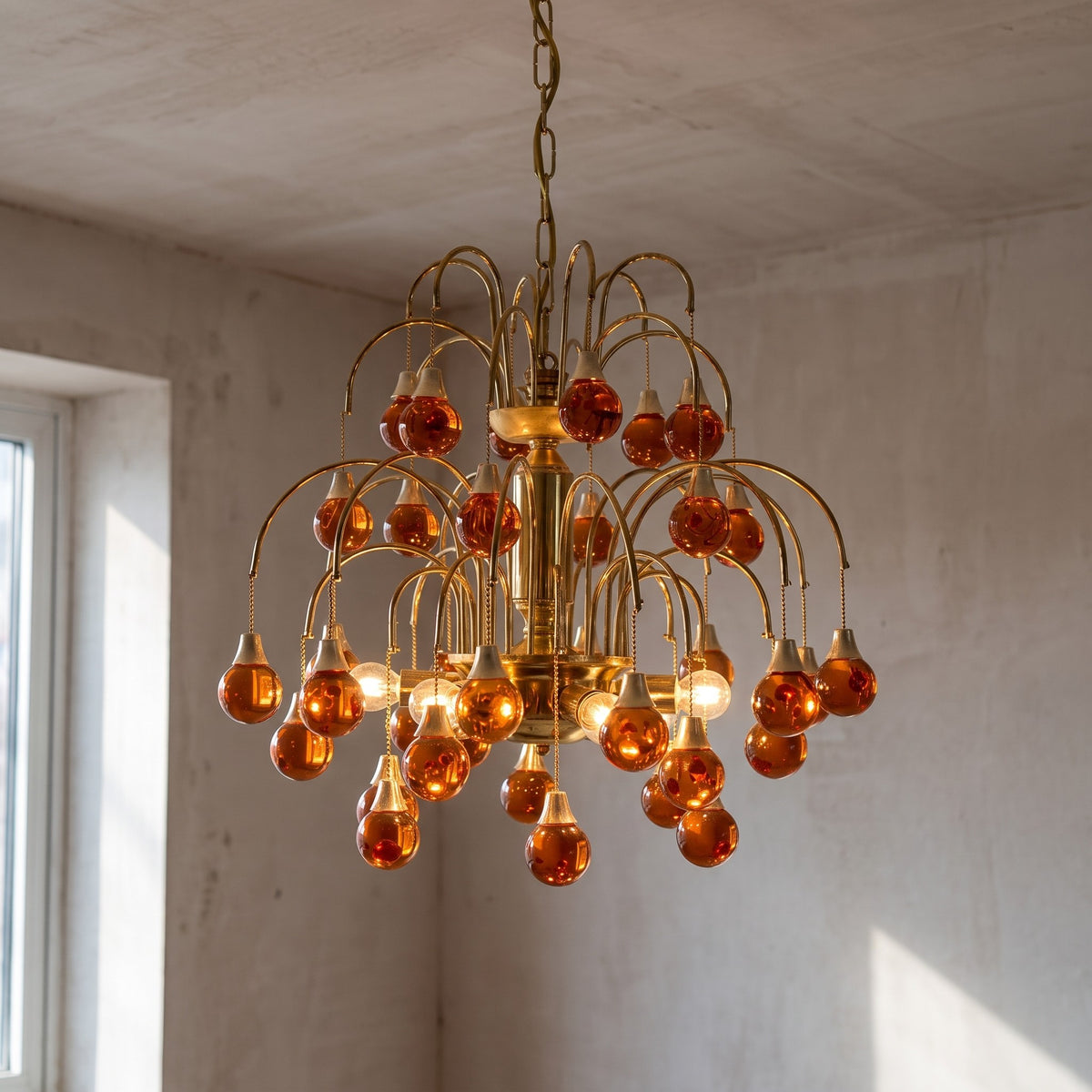 Vue d'ensemble du lustre Art Déco, présentant sa structure en fer doré et ses multiples pampilles en verre orange ambré, parfait pour un salon.