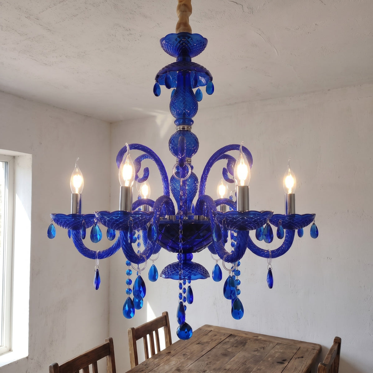 Perspective du lustre style Murano vu du dessous, soulignant la complexité de son montage et ses reflets.
