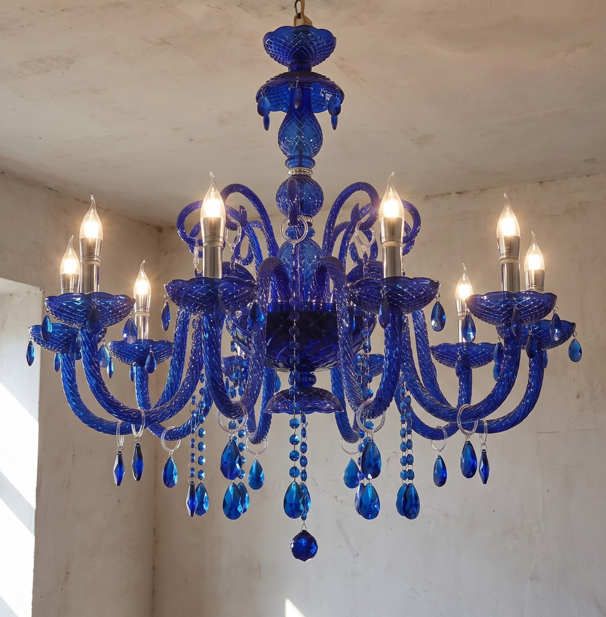Lustre cristal bleu saphir style Murano, capturant la lumière dans un salon élégant, créant une ambiance sophistiquée.