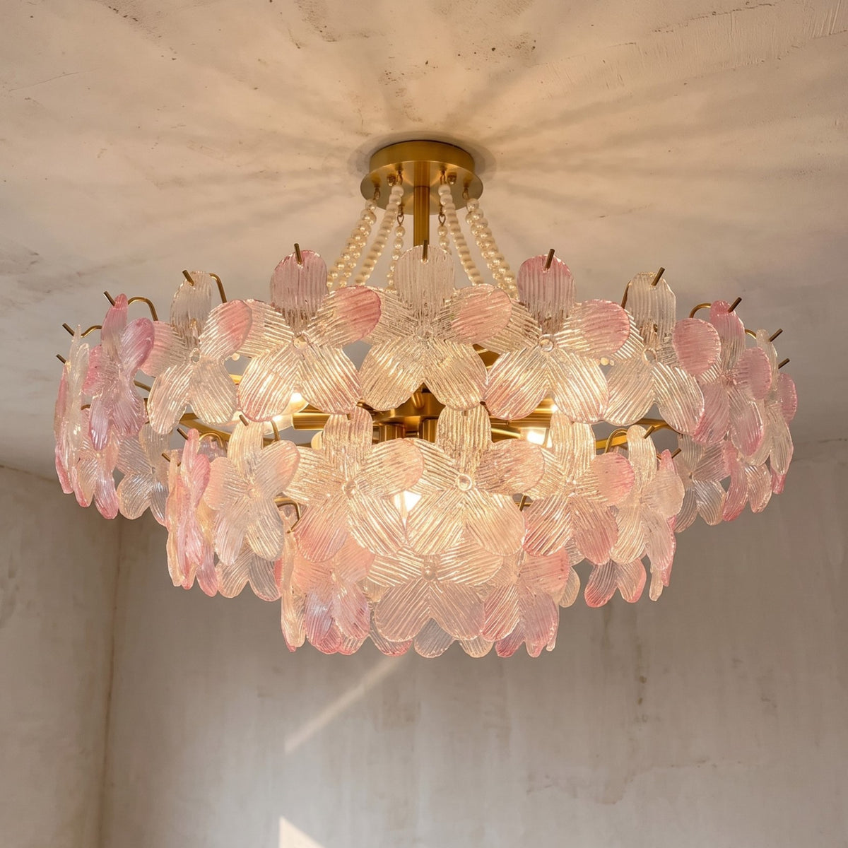 Lustre floral style Murano en verre rose pâle de 80 cm de diamètre, illuminant un salon moderne avec élégance.