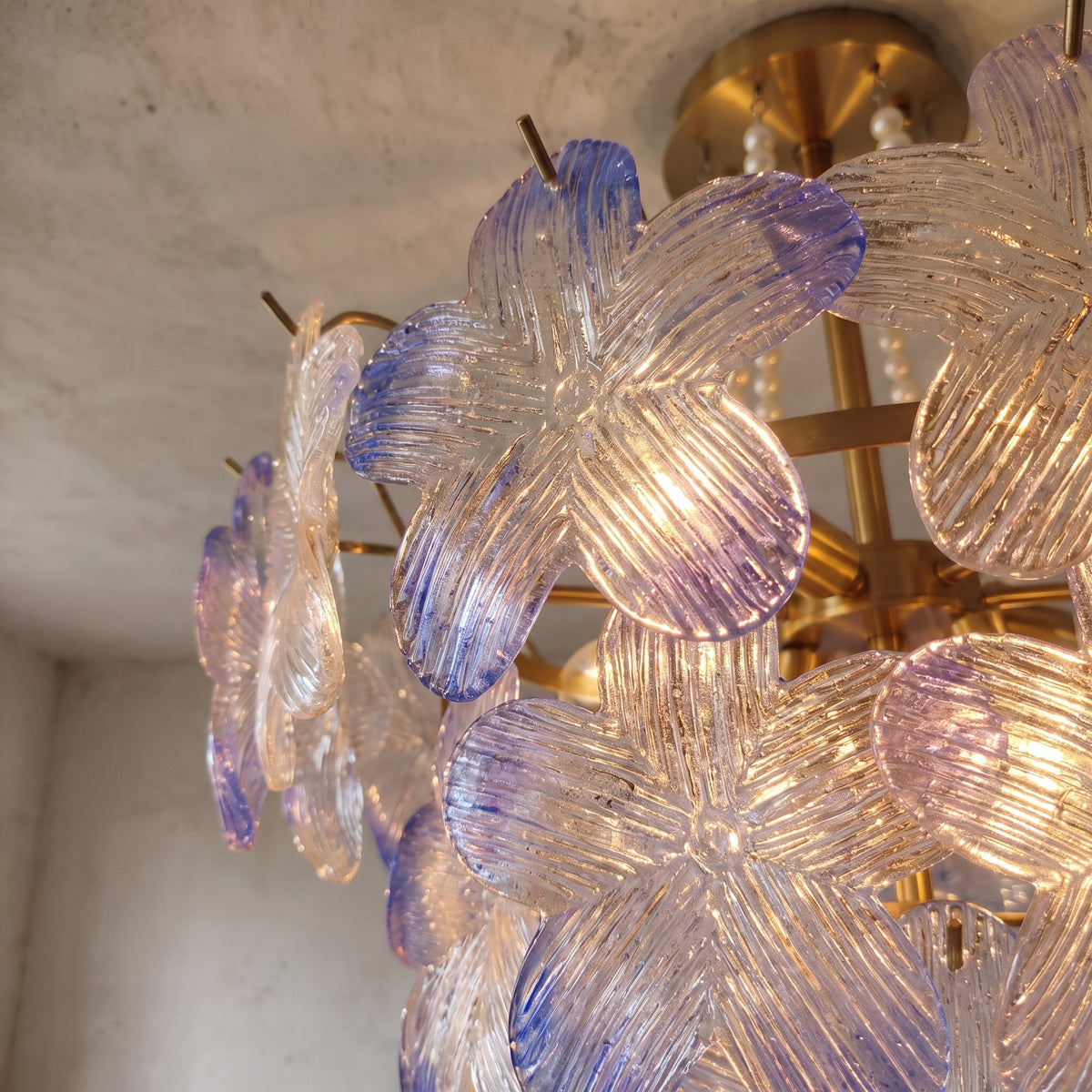 Détail de la structure en fer doré et du système de fixation au plafond, assurant une installation stable et sécurisée pour ce luminaire floral.