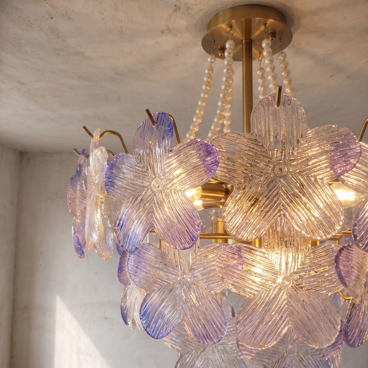 Lustre allumé, diffusant une lumière chaude à travers ses 9 ampoules E14, créant une ambiance accueillante dans une chambre à coucher élégante.