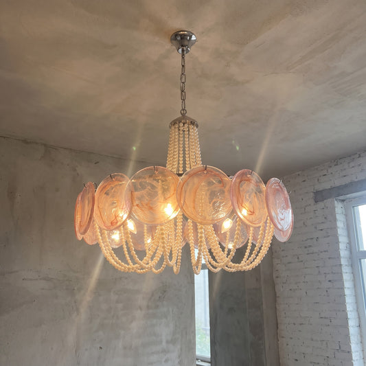 Lustre rond Art Déco avec disques de verre rose poudré et perles décoratives, illuminant élégamment un intérieur moderne.