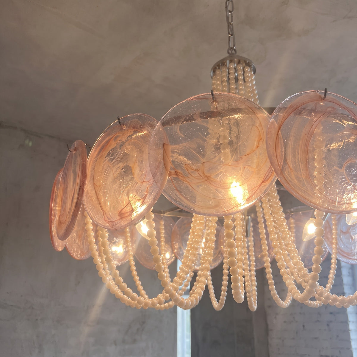 Détail des cascades de perles décoratives pendant sous les disques de verre, ajoutant une texture riche à la suspension.
