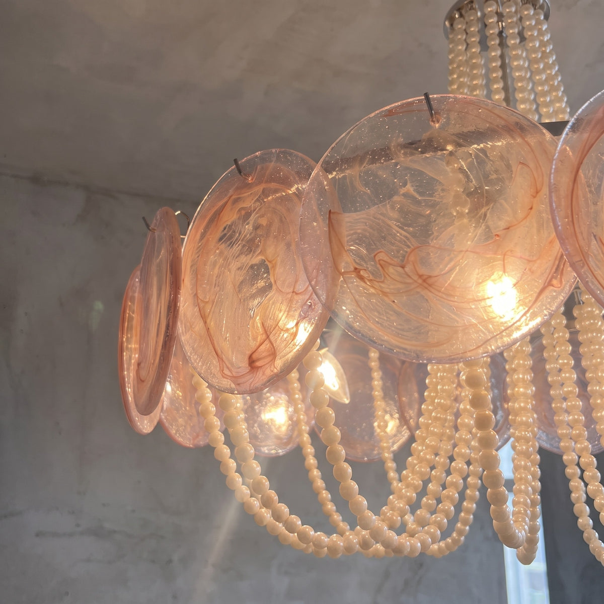 Le lustre Art Déco suspendu au plafond, mettant en valeur sa structure en métal chromé brillant et son design intemporel.