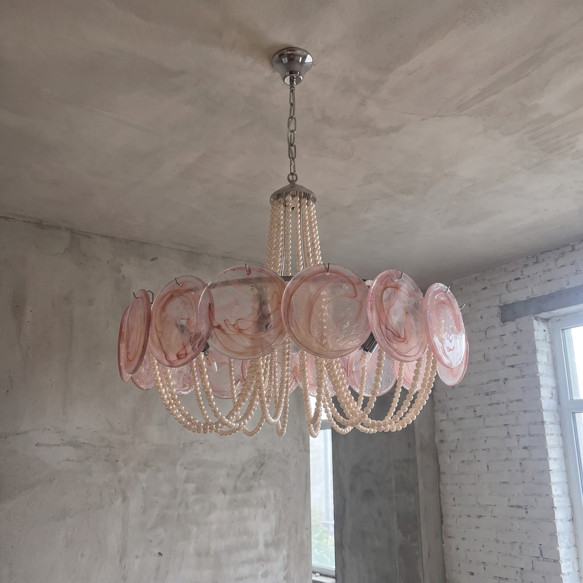 Effet de lumière du lustre allumé, révélant la douce lueur émise par les 8 ampoules E14 à travers le verre rose poudré.