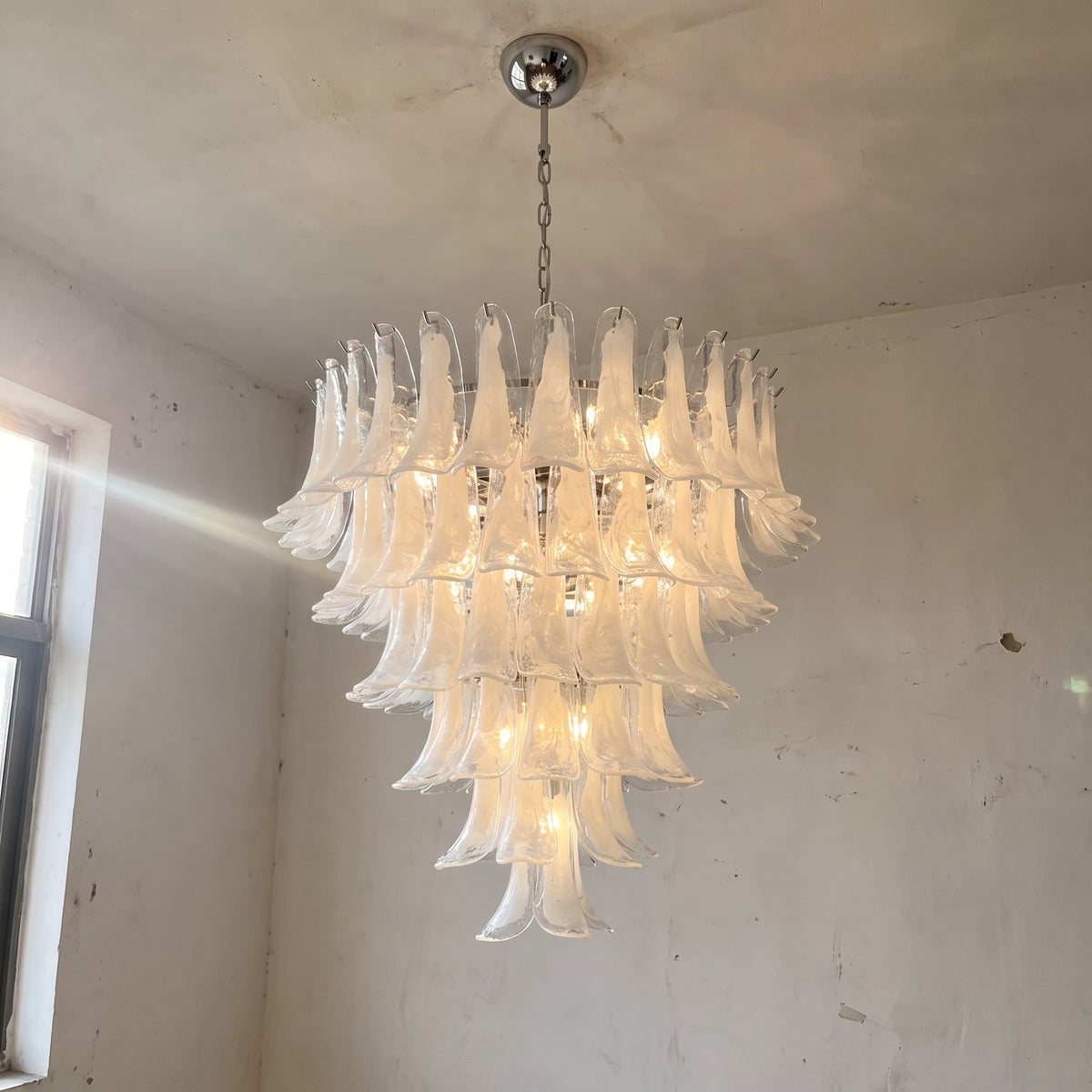 Vue d'ensemble du grand lustre style Murano blanc opalescent, illuminant un salon moderne avec élégance et raffinement.