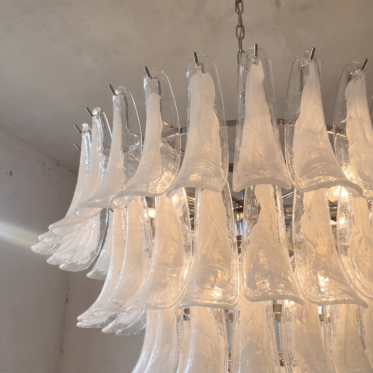 Le lustre style Murano, éteint, montrant la structure métallique chromée et la forme sculpturale des pétales de verre.