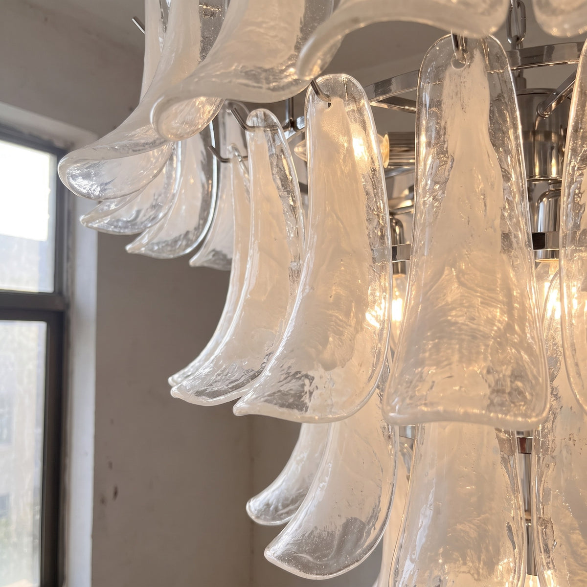 Détail rapproché des pétales de verre blanc opalescent du lustre, révélant la texture unique et l'éclat diffusé.