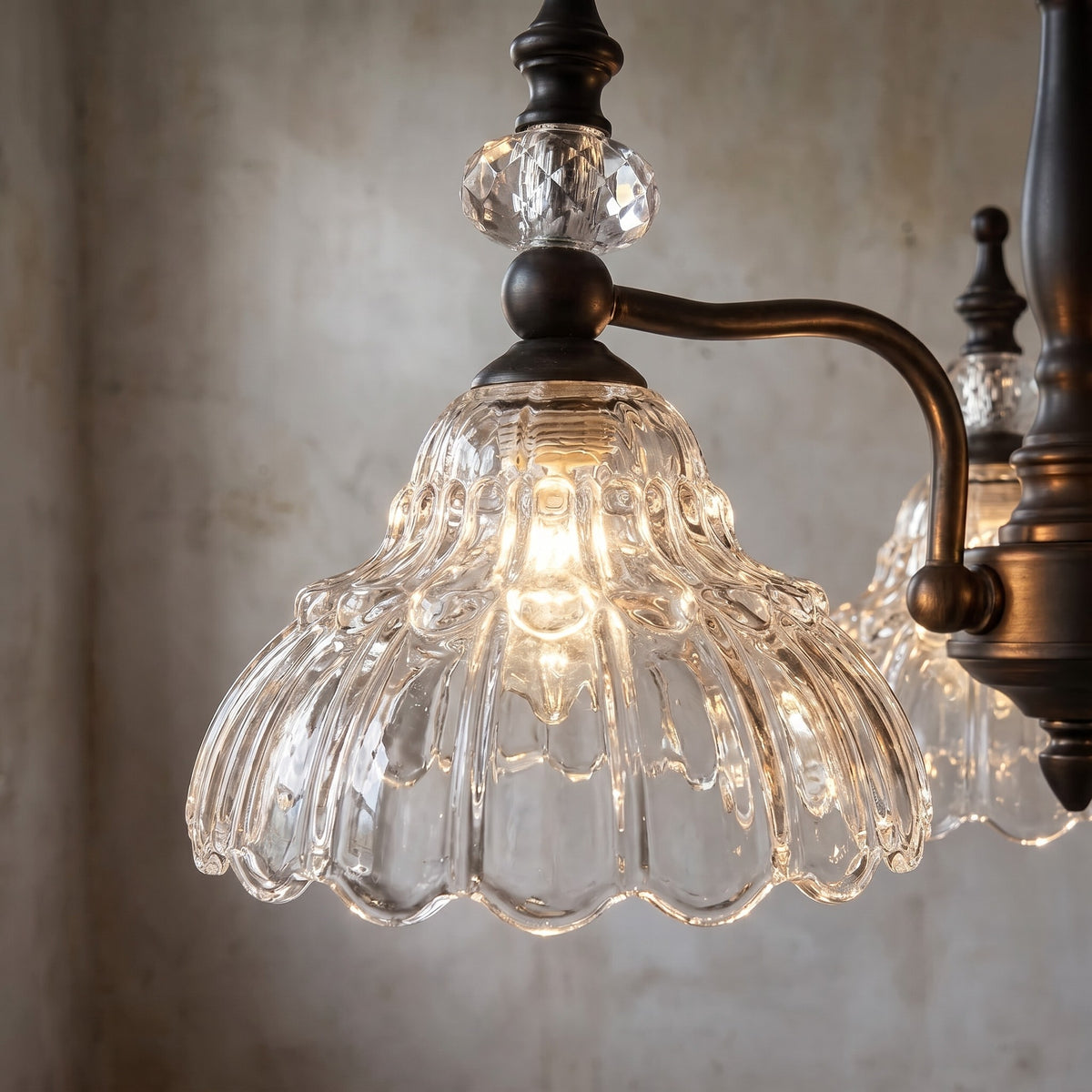 Profil latéral du lustre en verre sculpté et métal bronze antique, montrant la finesse des bras et la chaîne ajustable pour une hauteur optimale.