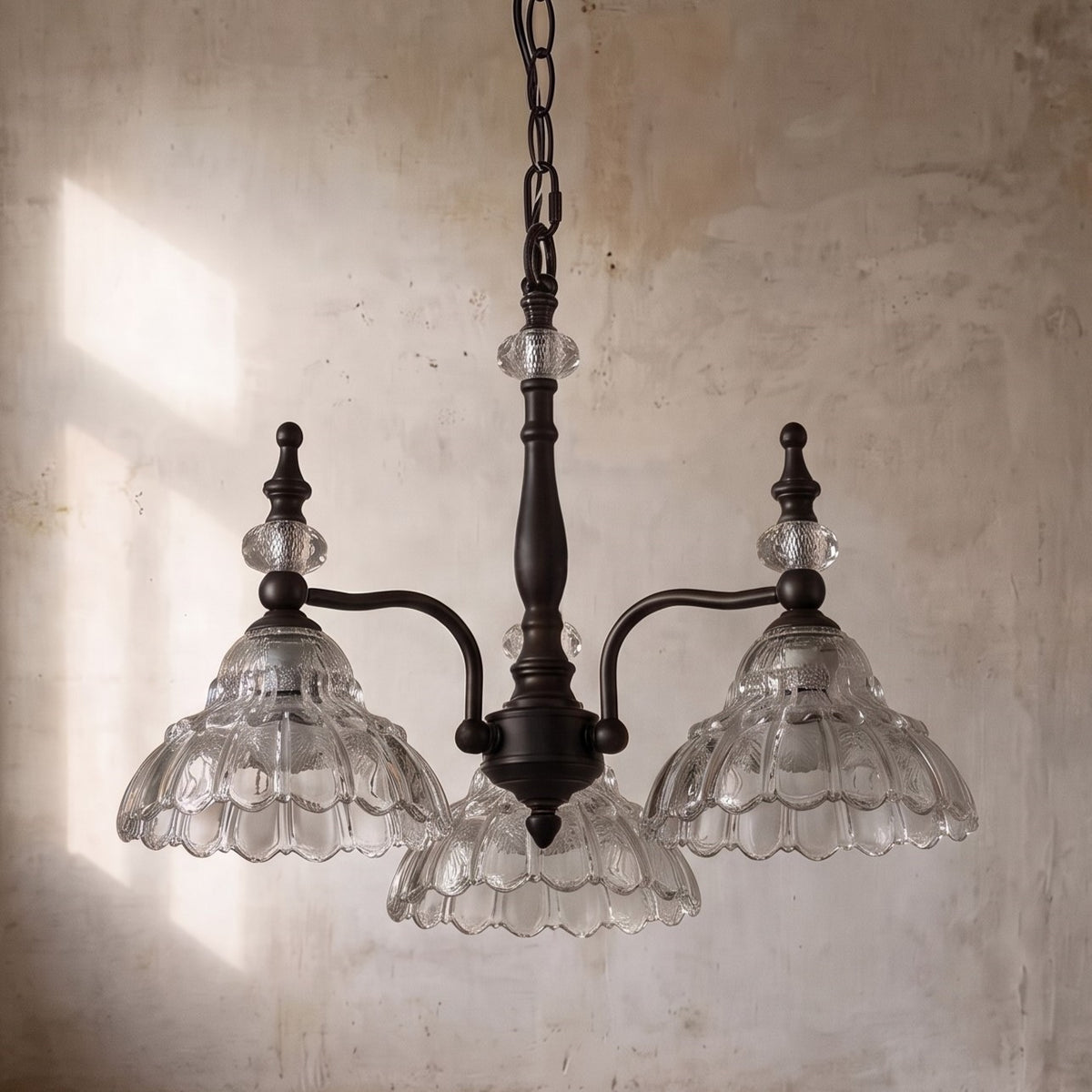 Détail rapproché d'un diffuseur en verre transparent sculpté, révélant la texture florale et la diffusion douce de la lumière du lustre.