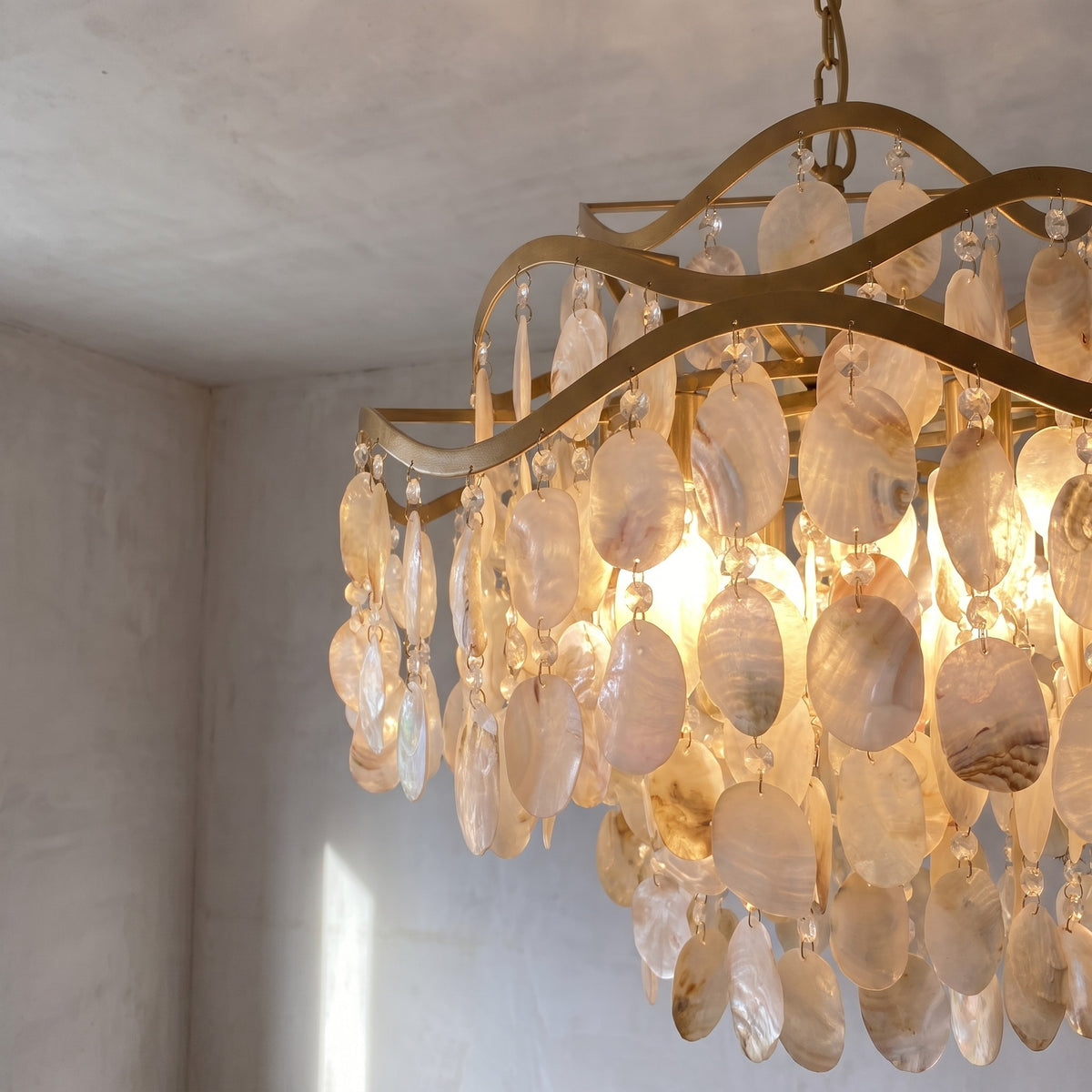 Détail des délicates pampilles de coquilles de nacre, arrangées en cascade sur le lustre, reflétant la lumière avec un éclat doux et chaleureux.