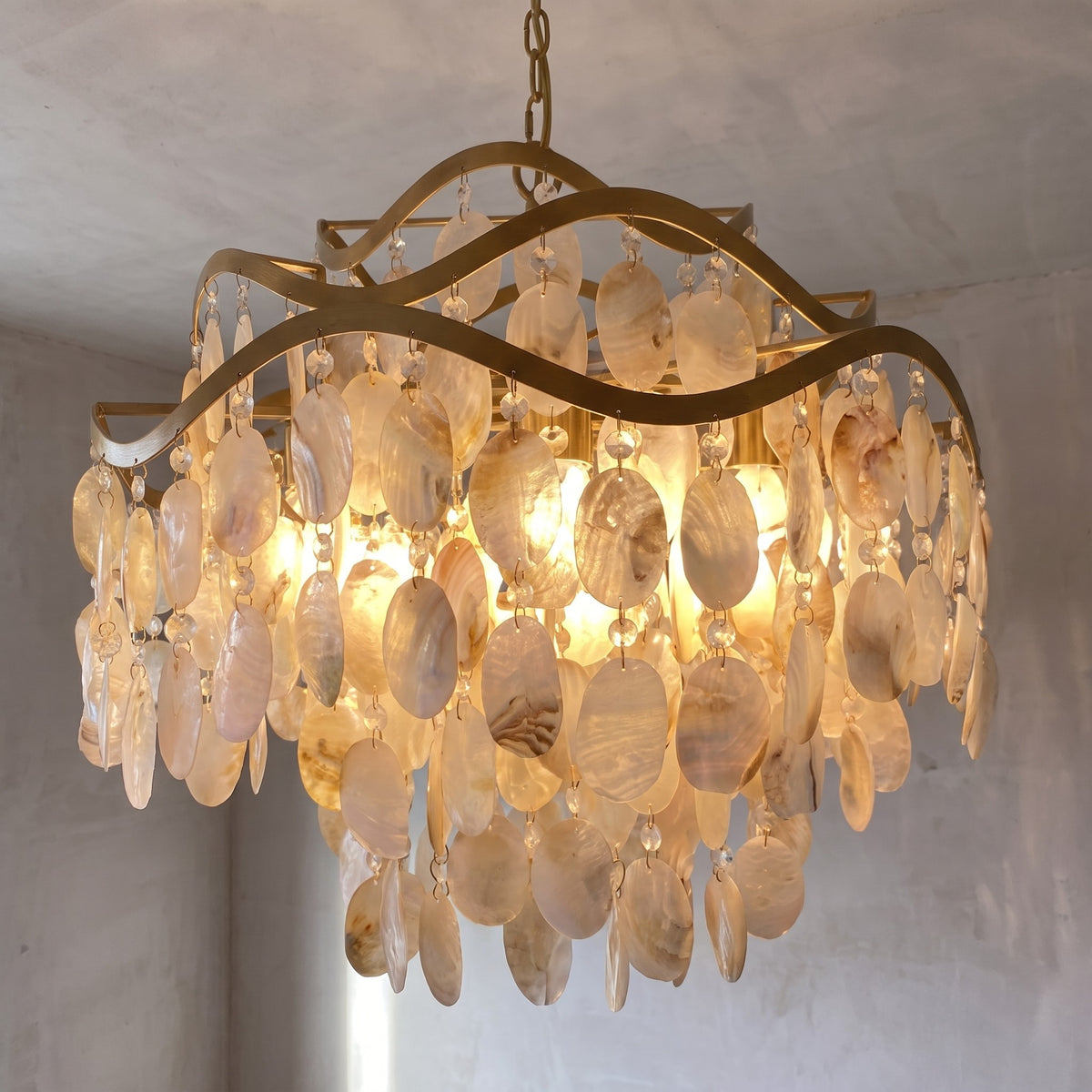 Lustre design en alliage métallique doré et nacre, suspendu élégamment, idéal pour illuminer une salle à manger avec raffinement et style.