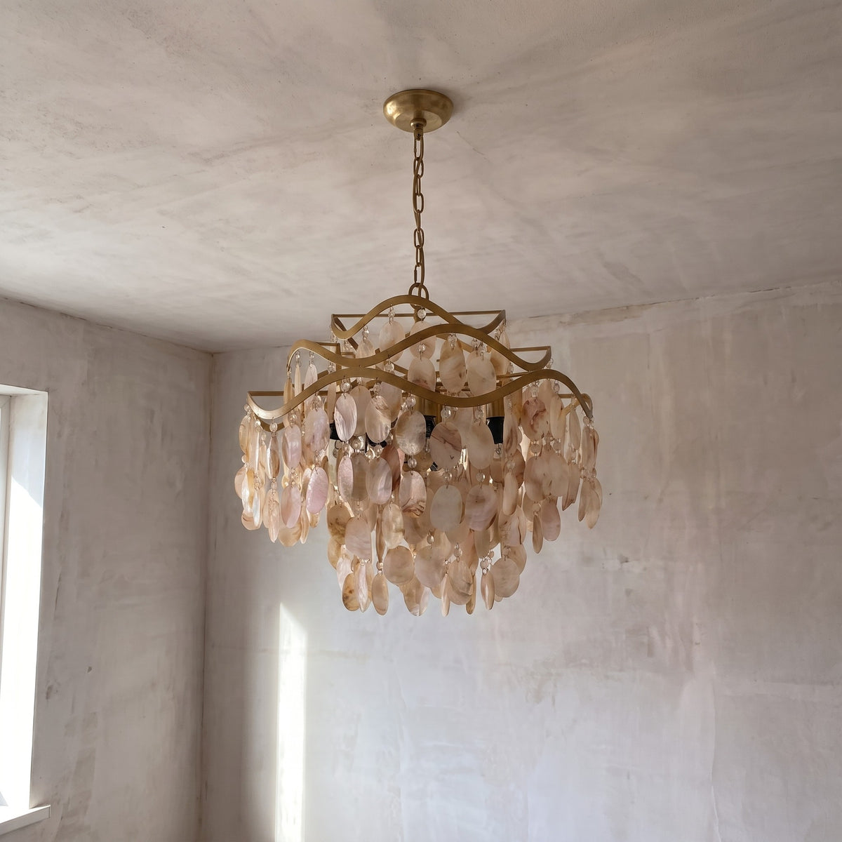 Lustre allumé, diffusant une lumière ambiante chaude à travers les coquilles de nacre, créant une atmosphère accueillante dans une chambre principale.