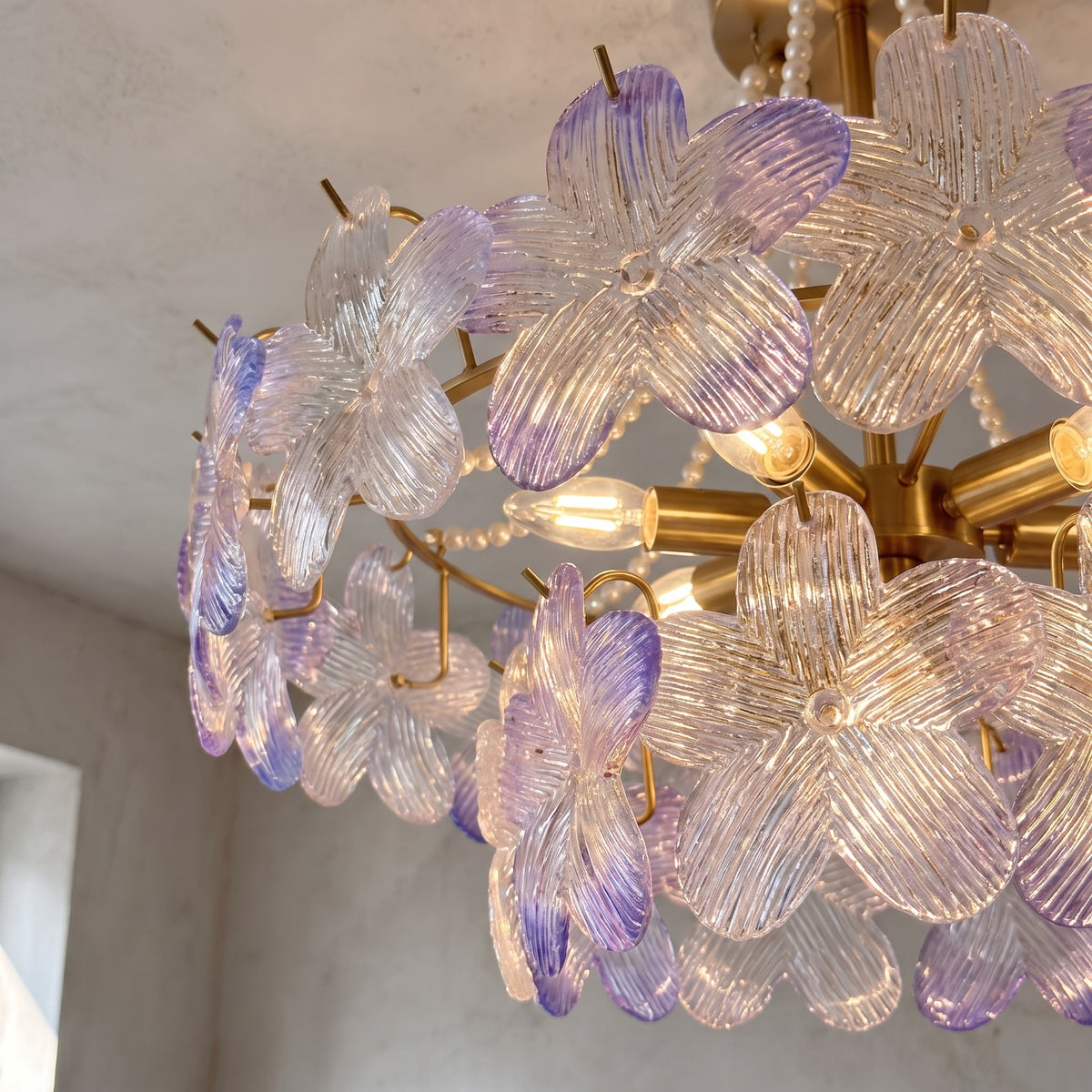 Détail des neuf ampoules E14 intégrées dans le lustre, entourées de pétales de verre translucide aux reflets changeants.