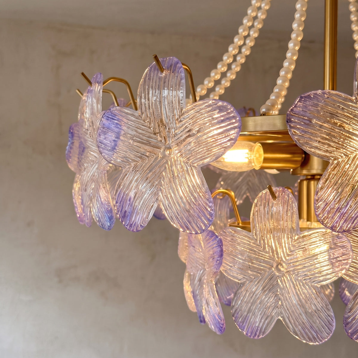 Vue de près des perles décoratives et de la structure en fer doré, soulignant l'élégance et la finition raffinée du luminaire.