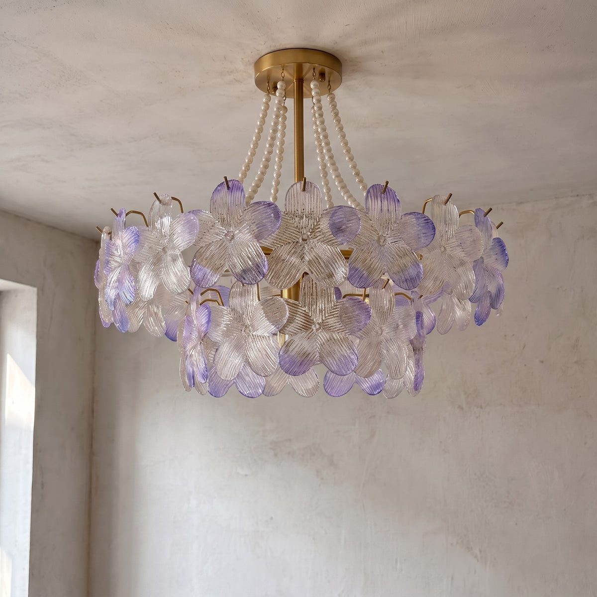 Lustre allumé, diffusant une lumière douce et colorée à travers ses multiples pétales de verre, idéal pour une chambre.