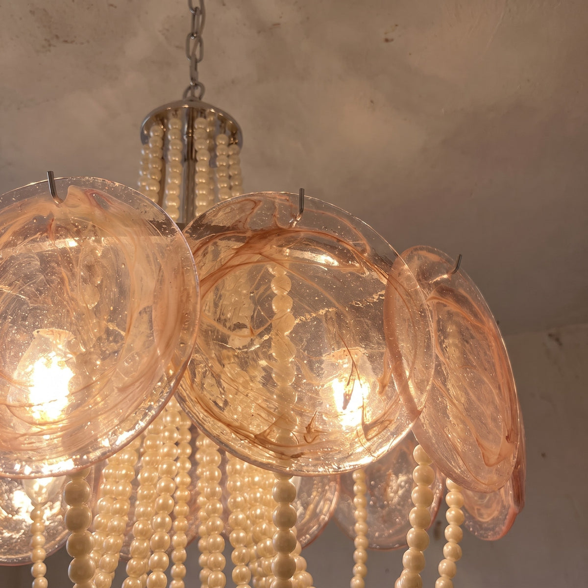 Lustre inspiré de Murano allumé, diffusant une lumière chaude et accueillante, idéal pour une ambiance cosy dans la salle à manger.