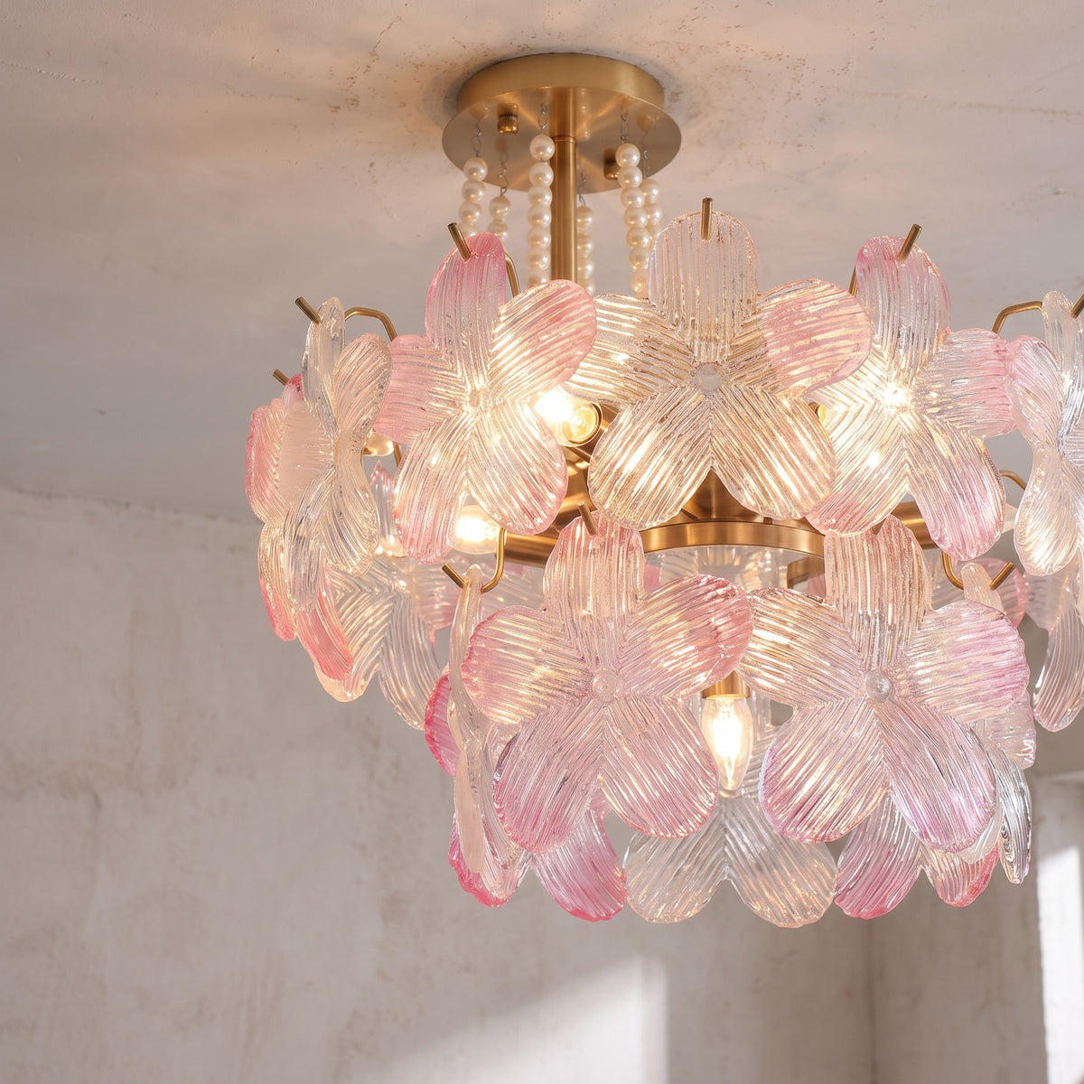 Lustre plafonnier rose allumé, diffusant une lumière chaude et accueillante, créant une ambiance romantique et douce dans une chambre élégante.