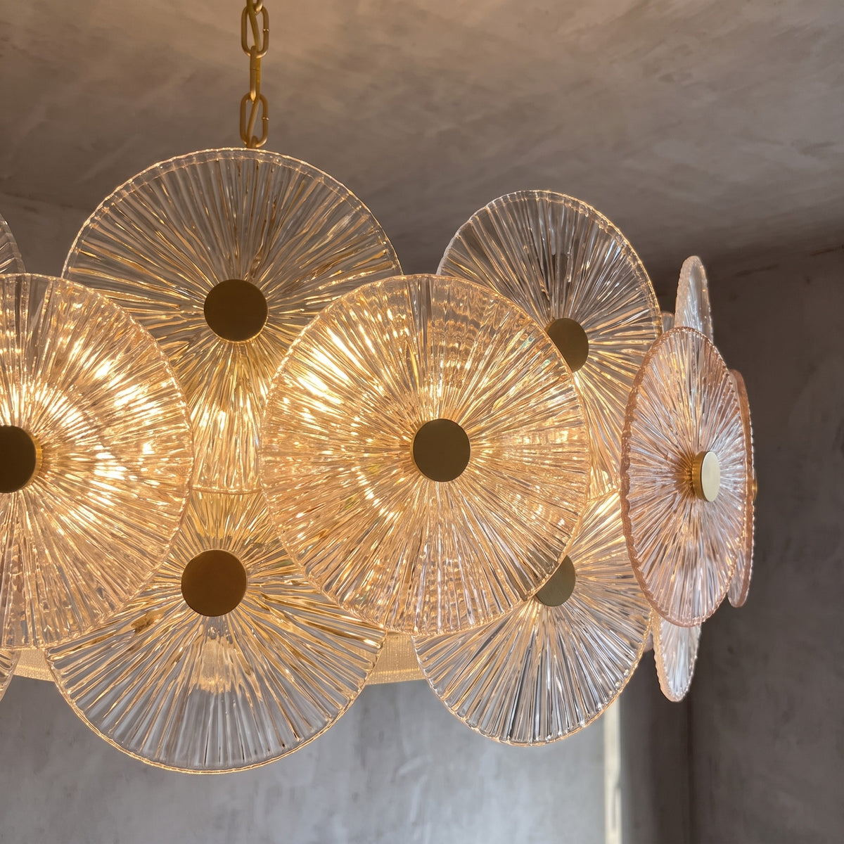 Lustre d'inspiration Murano accroché au plafond d'une salle à manger, diffusant une lumière chaude et accueillante.