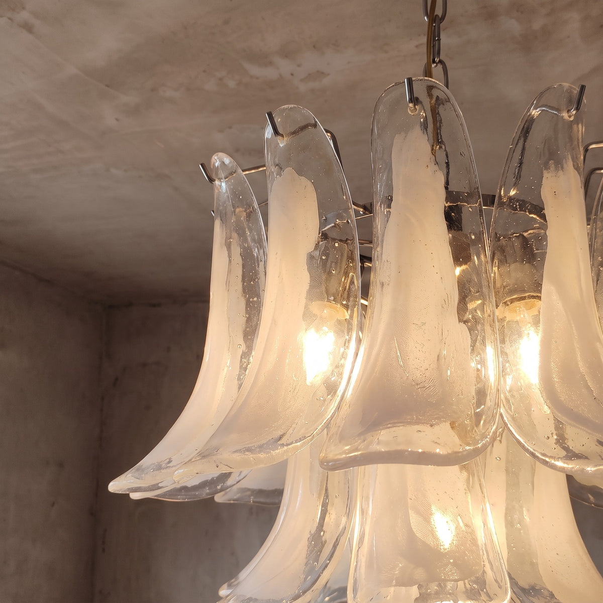 Détail gros plan d'un pétale de verre opalin du lustre, montrant sa texture délicate et sa diffusion lumineuse unique.