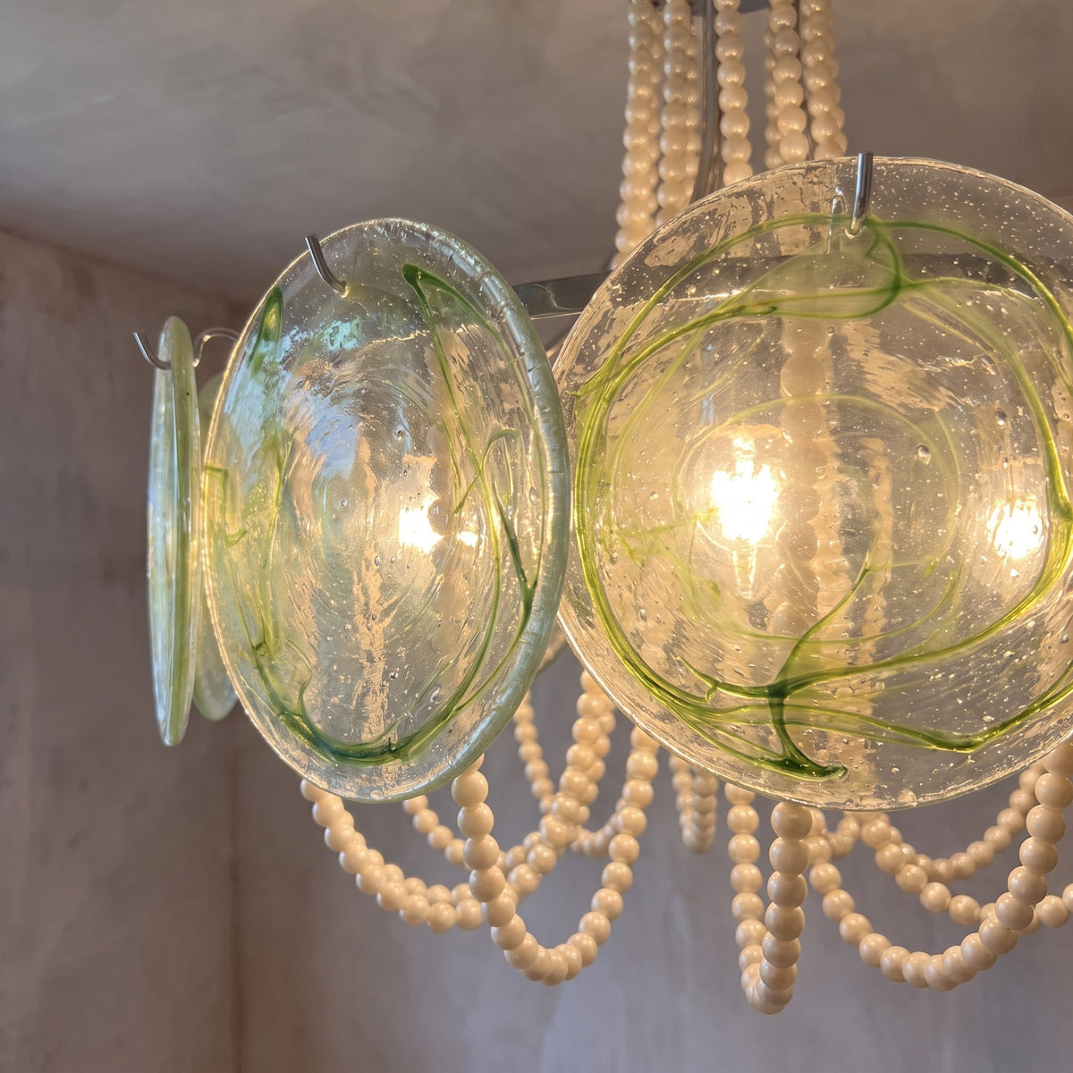 Le lustre style Murano allumé, diffusant une lumière douce et chaleureuse idéale pour un salon cosy.
