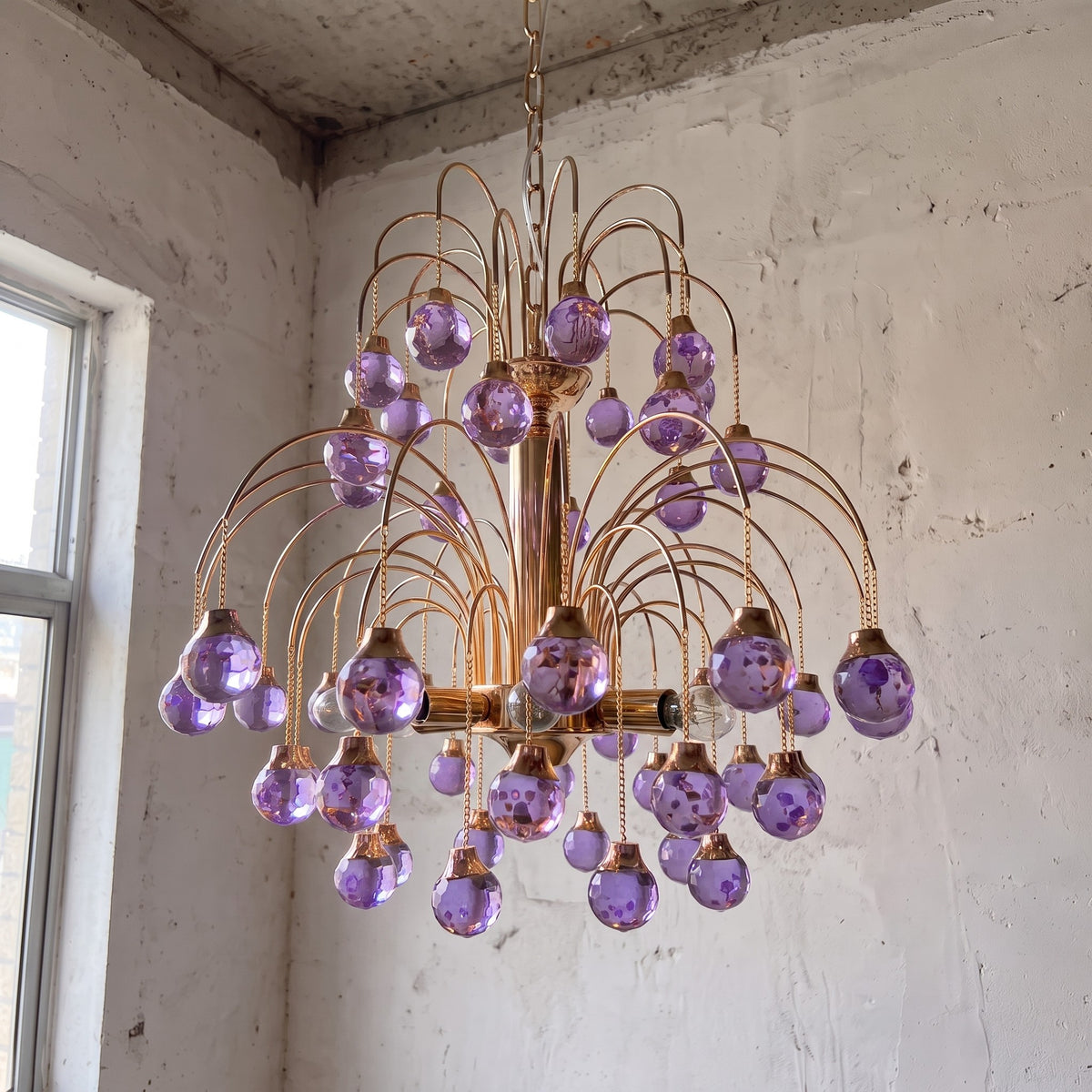 Suspension élégante en verre soufflé violet, créant un effet de cascade lumineuse, parfaite pour une salle à manger raffinée.
