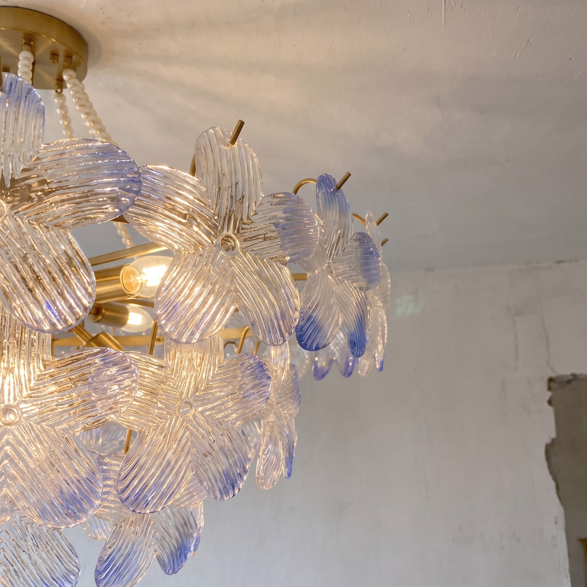 Détail du montage semi-encastré du lustre, présentant le bras standard de 20 cm et le châssis en fer de 12 cm de diamètre, avec les perles.