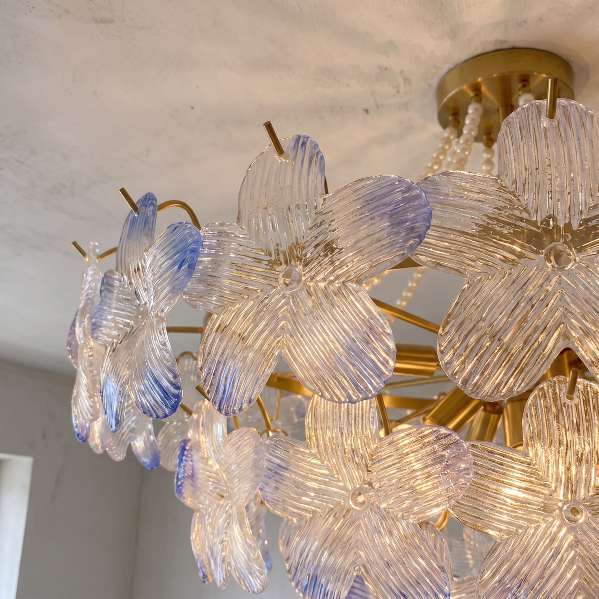 Vue rapprochée d'un lustre plafonnier avec ses pétales en verre texturé irisé bleu-lavande, montrant la richesse des détails et la qualité.