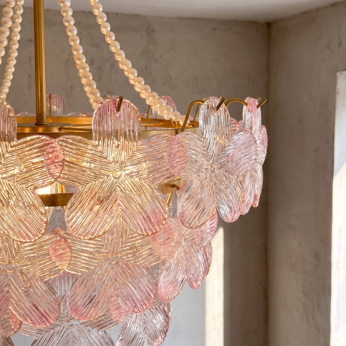 Lustre suspendu, montrant sa structure en fer doré et les chaînes de perles, soulignant le design luxueux et raffiné.