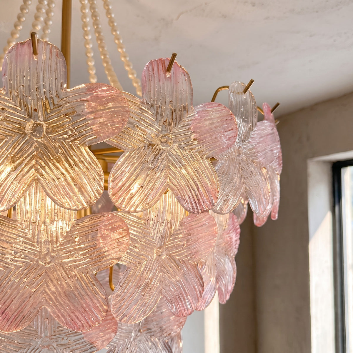 Lustre rose Murano en situation dans une chambre, créant une ambiance romantique et sophistiquée avec sa lumière.