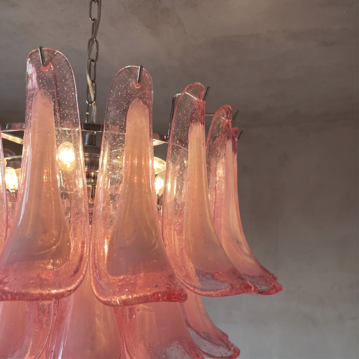 Détail des multiples couches de pétales de verre rose clair, créant un effet visuel texturé et captivant pour ce luminaire.