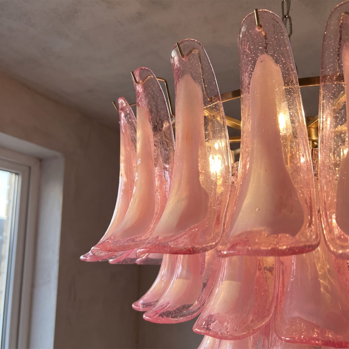 Lustre haut de gamme rose avec structure en métal chromé, idéal pour une chambre principale ou une salle à manger moderne.