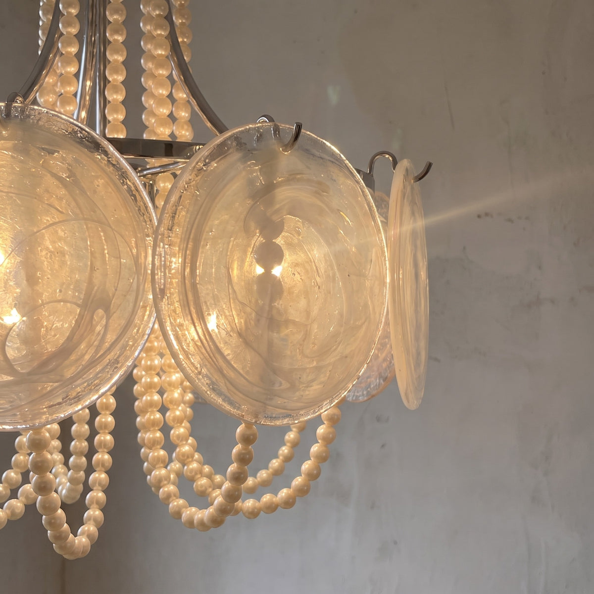 Profil latéral du luminaire Art Déco, soulignant la disposition des perles et des éléments en verre autour de la structure métallique.