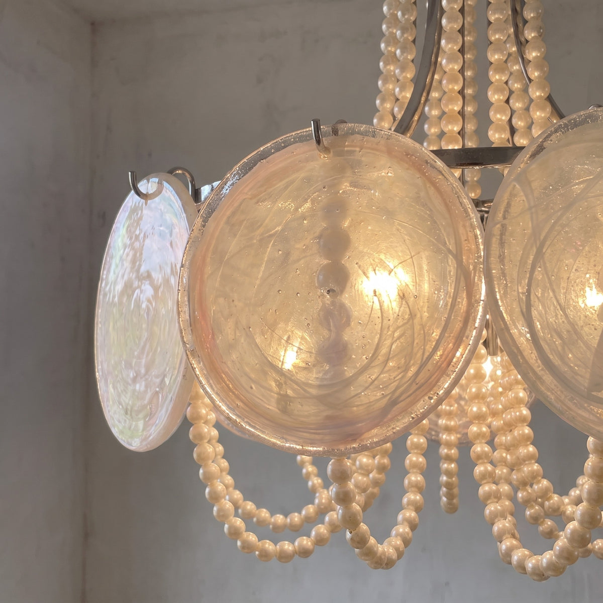 Détail rapproché des disques de verre opalescent reflétant la lumière, montrant la texture unique de ce luminaire élégant.