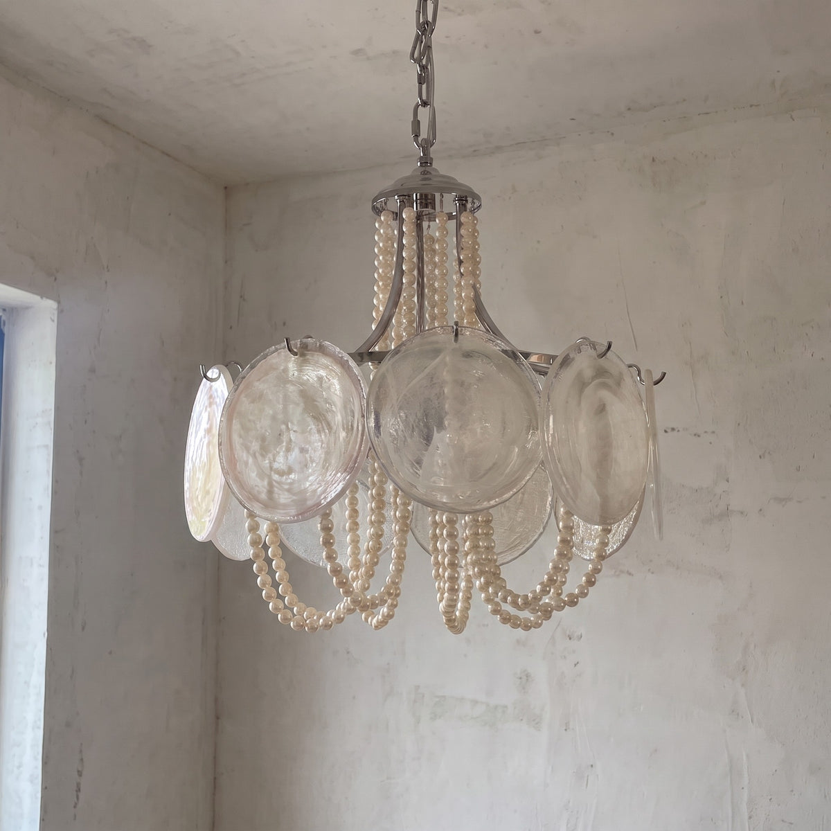 Le lustre allumé, diffusant une lumière douce et enveloppante, parfait pour une salle à manger ou un espace de détente raffiné.