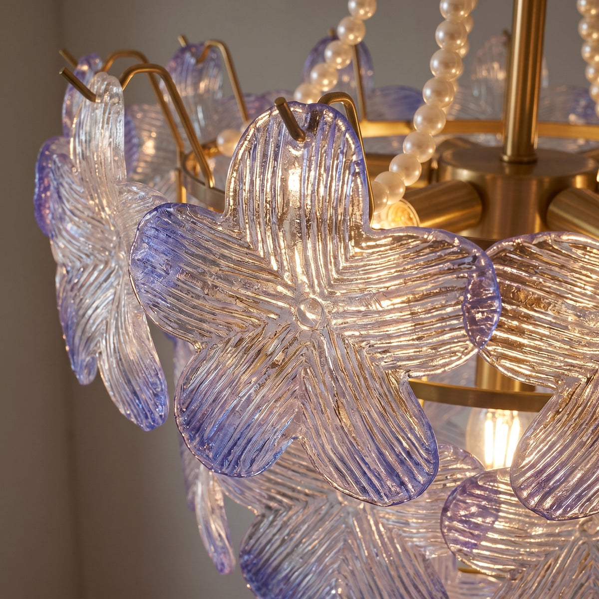 Détail rapproché des pétales de verre irisé, soulignant leur texture délicate et les subtils reflets de lumière rose et bleu.