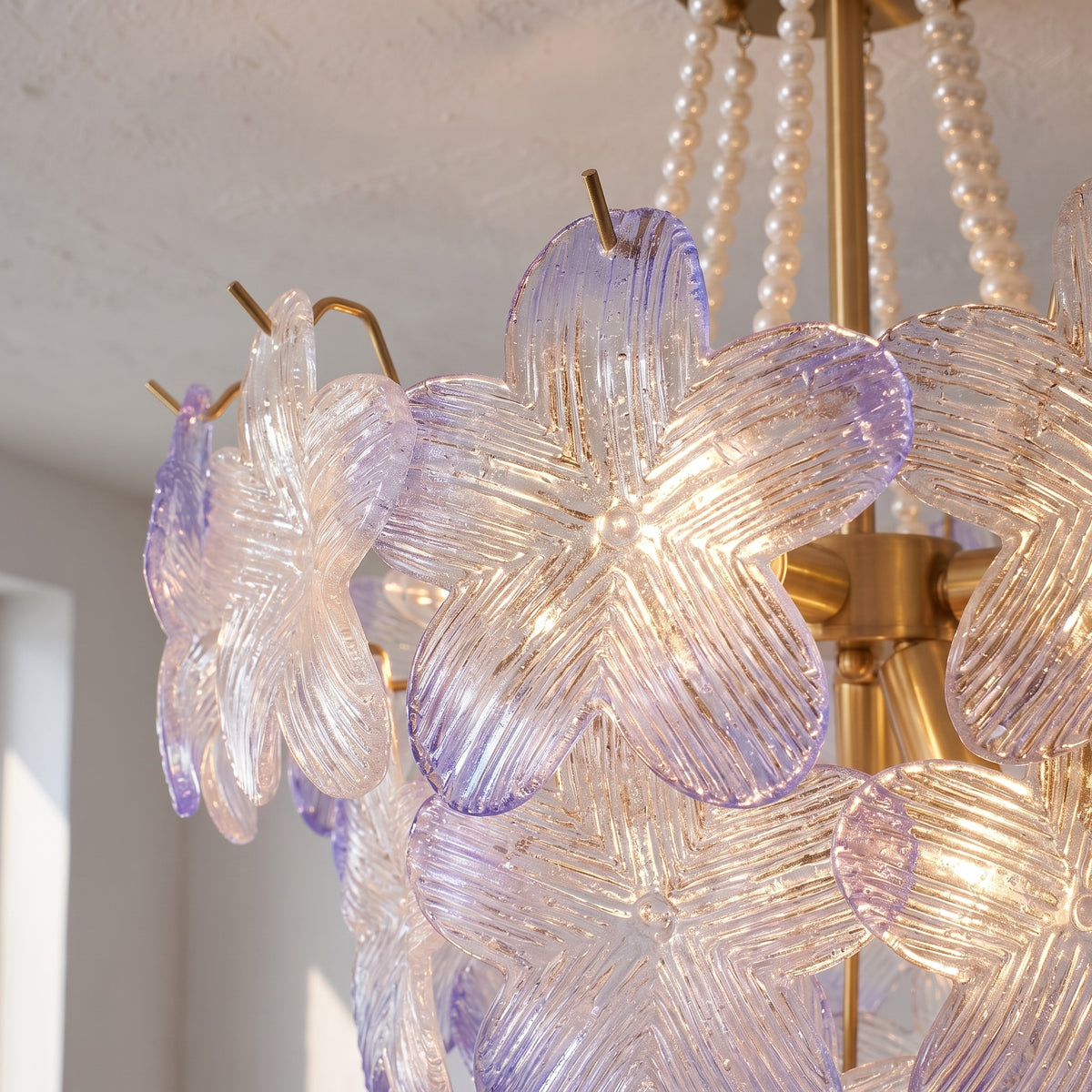 Perspective du lustre montrant les chaînes de perles blanches et la structure en laiton doré, ajoutant une touche de luxe.