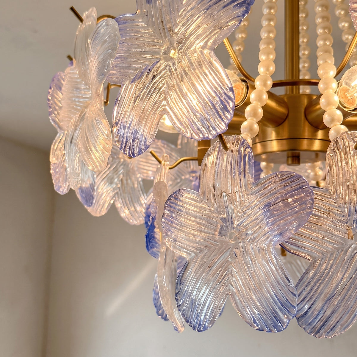 Lustre contemporain avec perles et structure en métal doré, créant une ambiance lumineuse douce dans une chambre cosy.