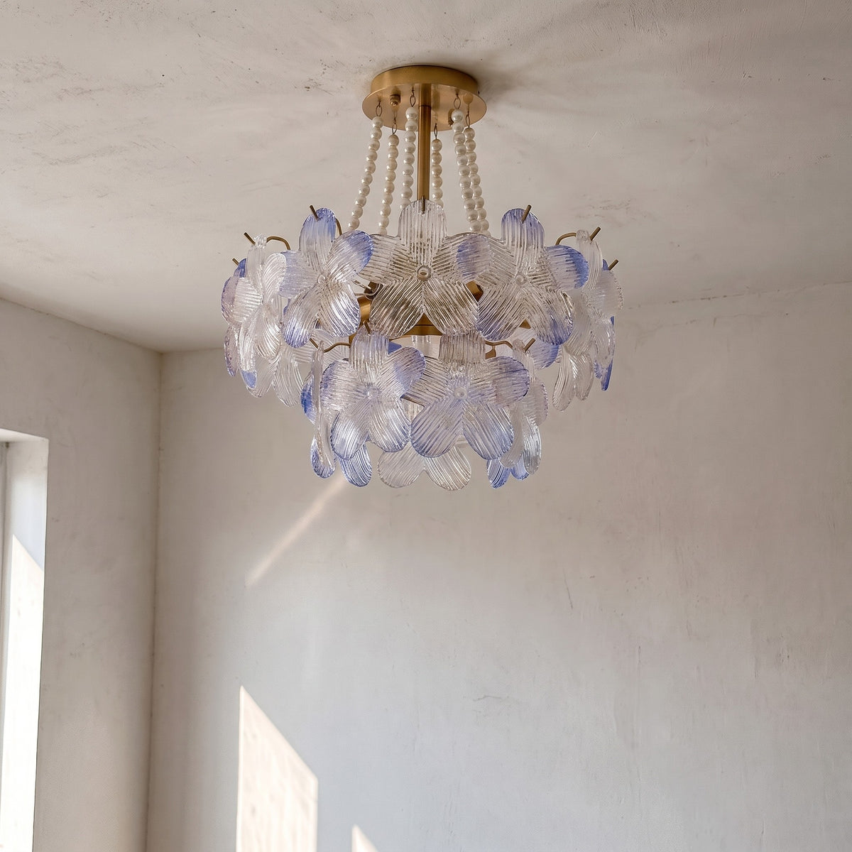 Le lustre allumé, diffusant une lumière chaude à travers ses pétales de verre, ajoutant une touche de luxe discret à la pièce.