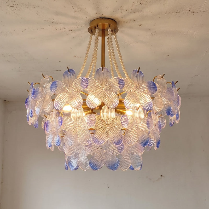 Vue d'ensemble du lustre style Murano, ses 12 douilles E14 illuminant les pétales de verre texturé aux nuances pastel bleutées et rosées, idéal.
