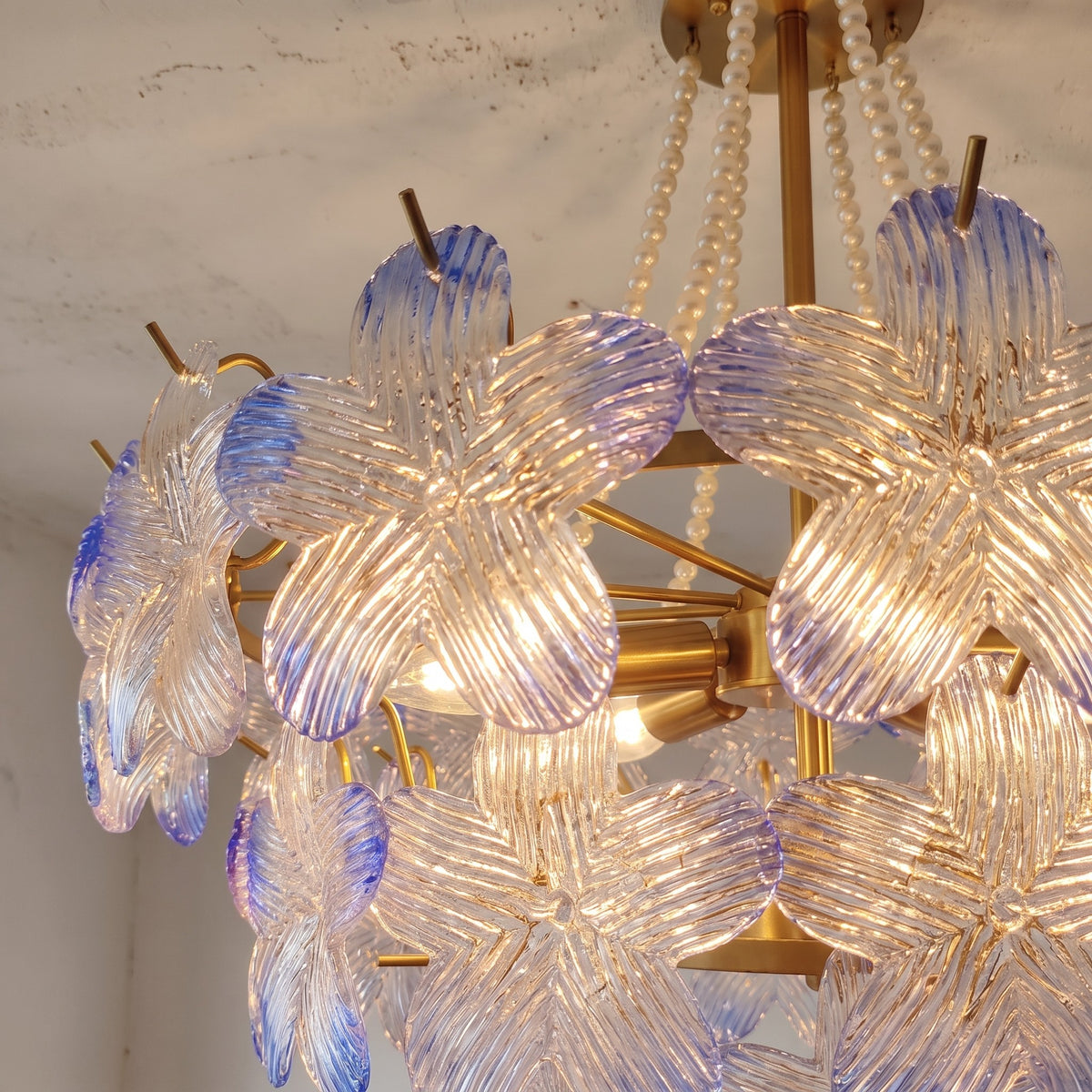 Le lustre suspension style Murano vu de côté, montrant sa structure en fer et ses perles décoratives, parfait pour créer une ambiance douce.