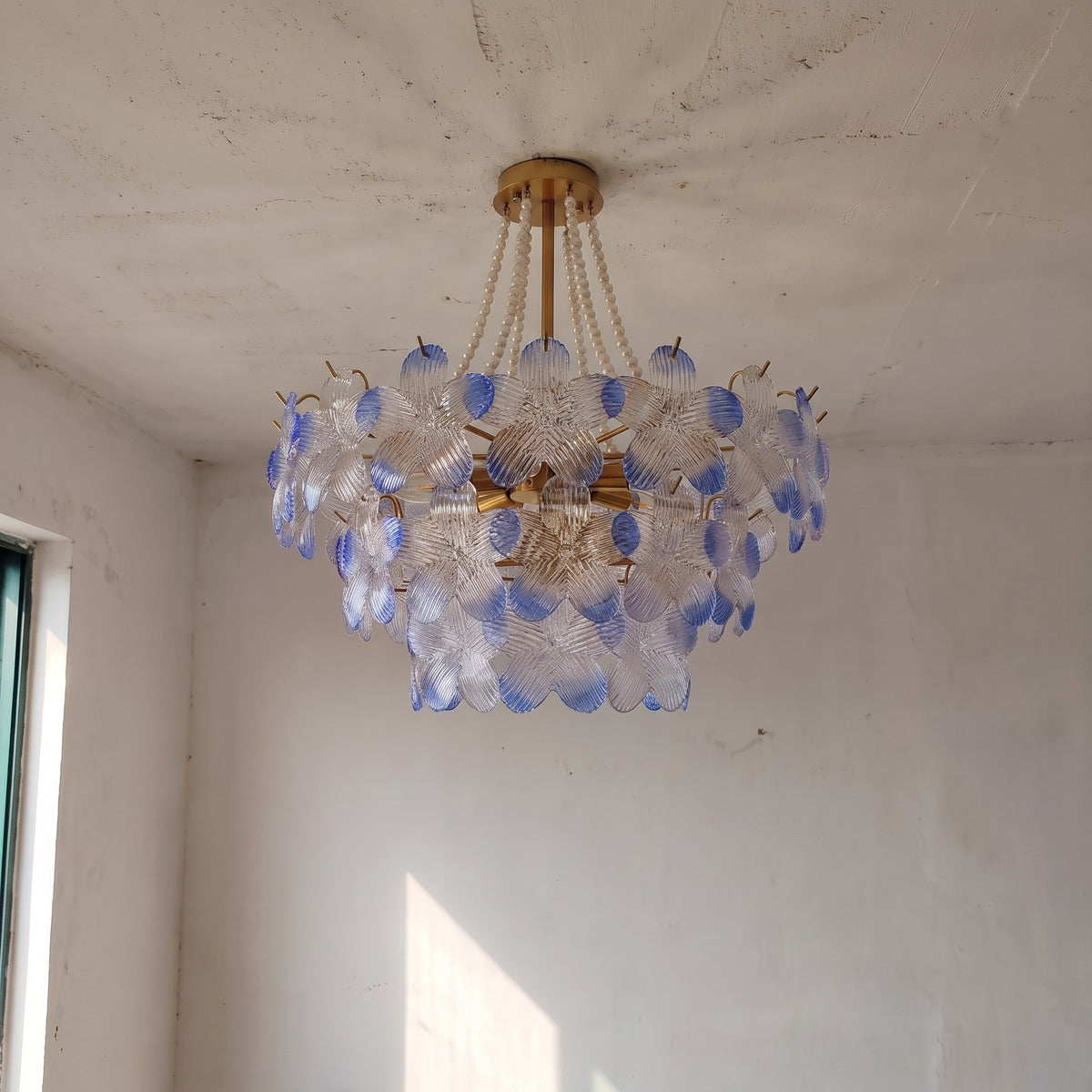 Gros plan sur les délicats pétales de verre soufflé, mis en valeur par la lumière, révélant les subtiles teintes pastel bleutées et rosées.